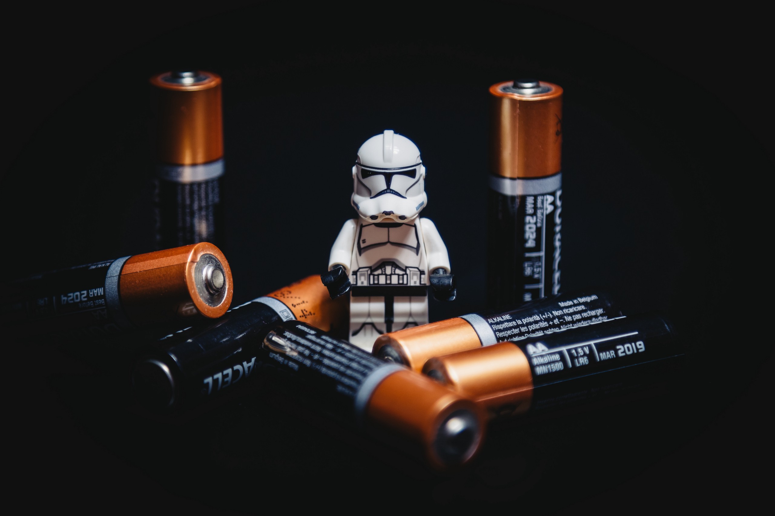 lego clone surrounded by 7 batteries, black background