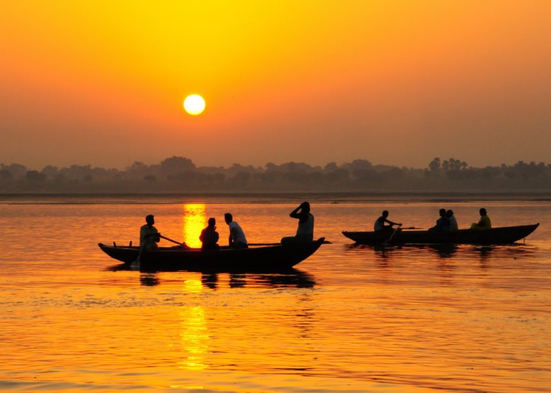 men in canoes in India during sunset