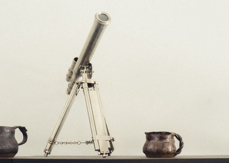 telescope, scale world, metal jars and a vase, wheat background