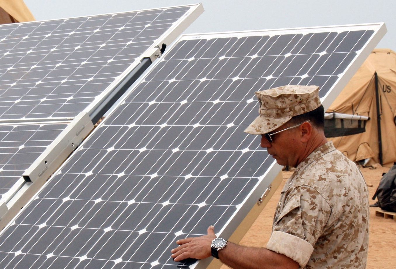 service members next to solar panels