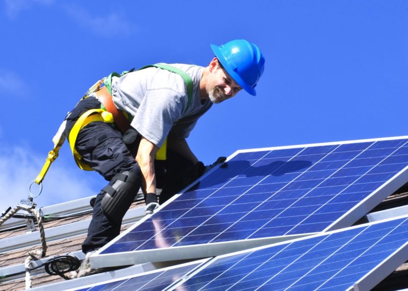 guy installing solar panels in the roof, blue helmet