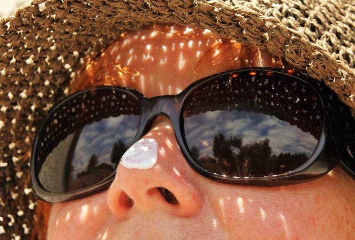 lady with a hat and sunglasses with solar protection cream
