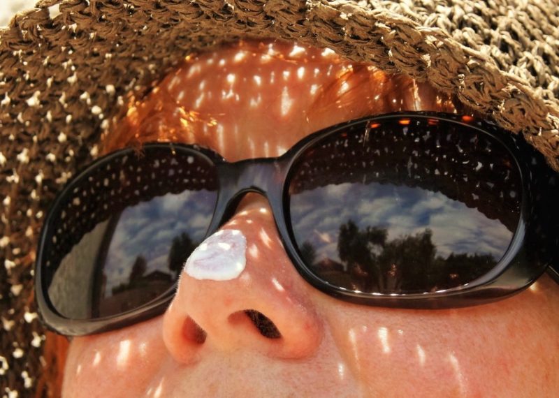lady with a hat and sunglasses with solar protection cream