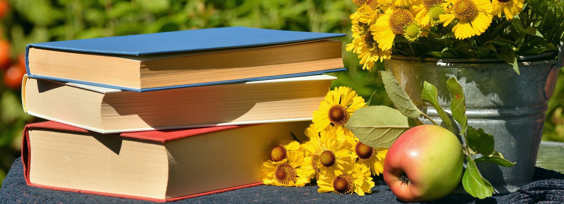 Books, apple and flowers on a jarden table