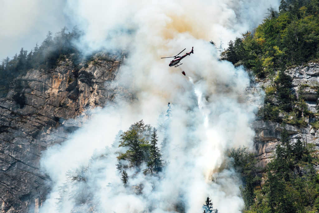 helicopter extinguishes forest fire on the slope of a mountain