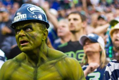 Seahawks fan with body paint like the hulk and a blue helmet with more fans of the team