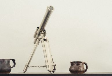 telescope, scale world, metal jars and a vase, wheat background