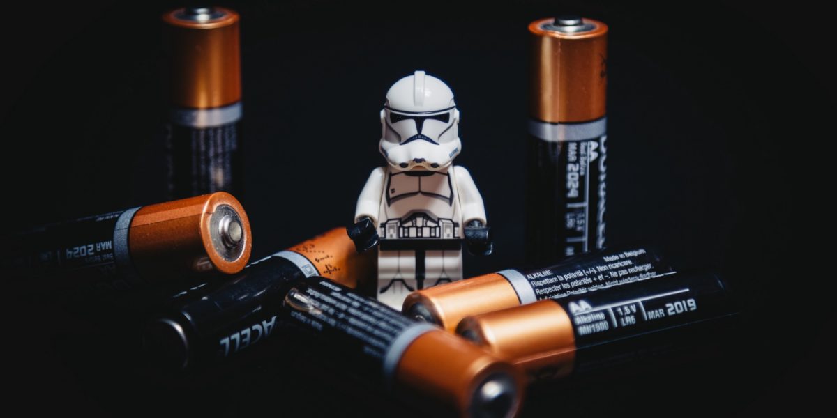 lego clone surrounded by 7 batteries, black background