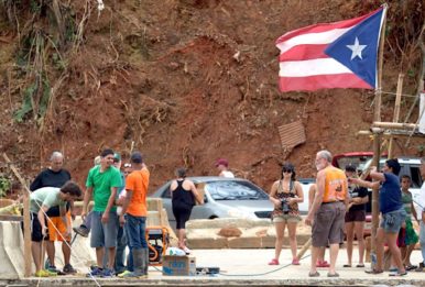 Villagers collect on bridge remnants to receive needed supplies in Utuado, Puerto Rico. Source: Andrea Booher, FEMA