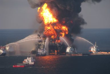 oil rig on fire with boats spraying water on it