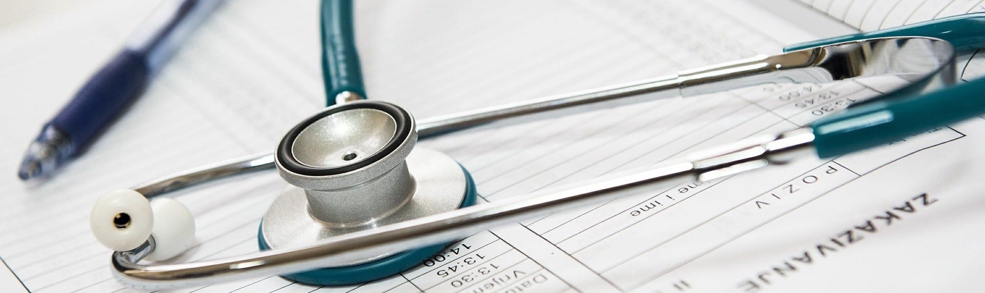 green stethoscope on clinic sheets